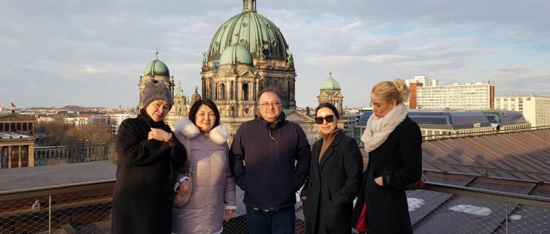 Participants of a CAC internship program on a rooftop in Berlin, with Berlin Cathedral behind them