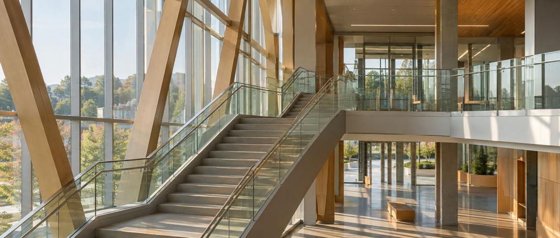 Modern glass-and-timber staircase and walkway inside a light-filled building interior, evoking structured progression.